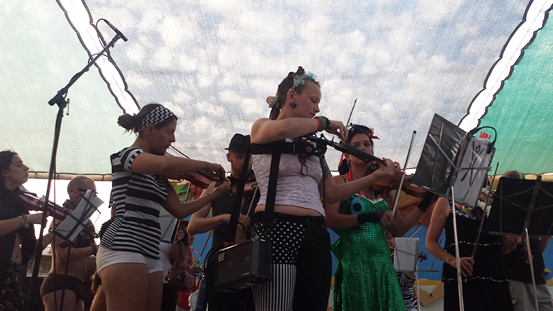 Madelaine Ripley and other violinists with the PlayaPops Symphony, the first-ever string orchestra at Burning Man, warm up before their performance at Center Camp