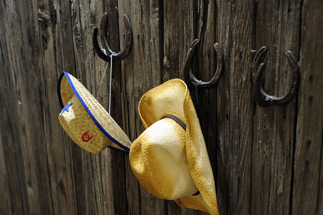 Cowboy hats hanging on low hooks for children to wear at NUMU's "It Takes a Village" exhibit. Photo by Adrienne Blaine.