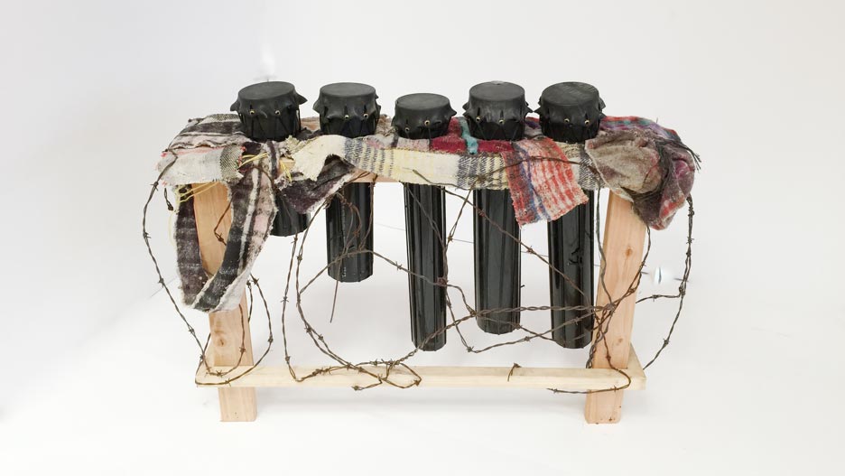 'Llantambores,' drums caped with skin made from inner tubes used to cross the Rio Grande in Texas and wedged into a structure fashioned out of carpet booties used by immigrants to hide their footsteps; barbed wire that once served as the fence between the two nations surrounds.