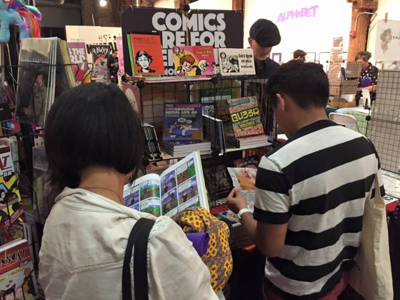 Visitors peruse the comics at the PRISM booth. 