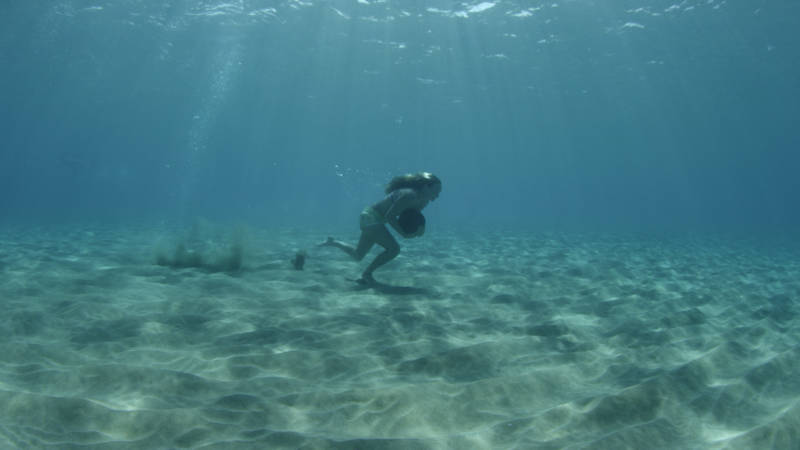 Paige Alms runs underwater with a heavy rock as part of her training to ride big waves.