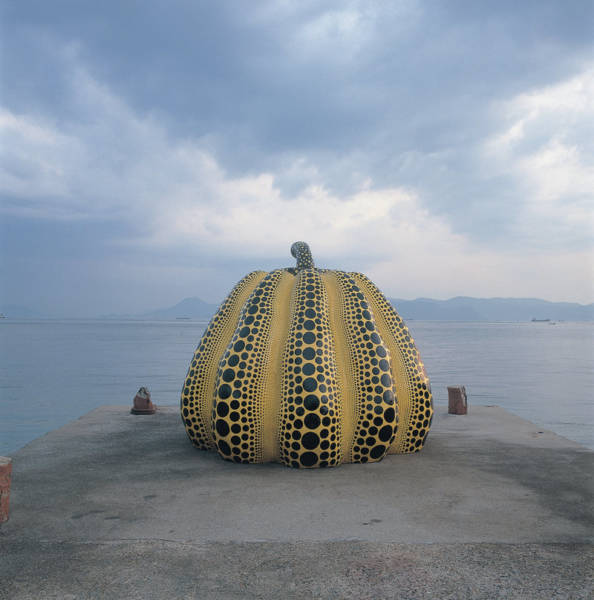 Yayoi Kusama's work "Pumpkin" perches at the end of an old concrete pier.