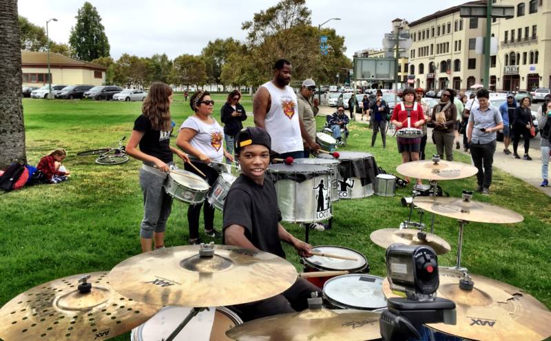 Aaron Davis at his drum kit at Eastshore Park with members of the drum corps Loco Bloco behind him