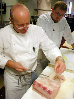 Oliveto Chef Paul Canales (left) cutting swordfish belly for a crudo. Watching him is intern Nick Hatten. Photo by Stuart Leavenworth