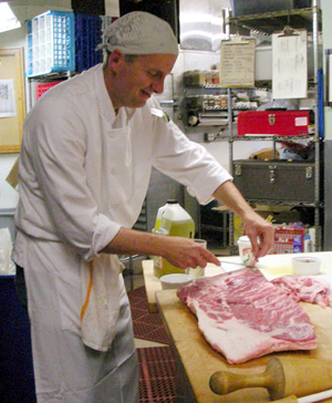 Stuart trims fat off of a pork belly for pancetta.