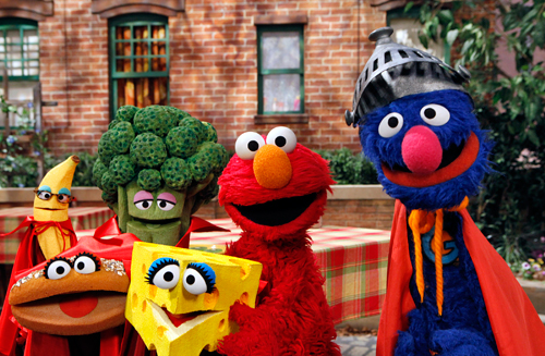 Elmo and Super Grover pose with the four healthy food groups (Fruits, Vegetables, Dairy, and Grains) as part of Sesame Street’s Food For Thought initiative. Copyright 2010 Sesame Workshop.  Photo by: Richard Termine.