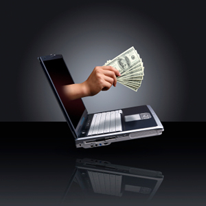 laptop with hand holding cash emerging from screen