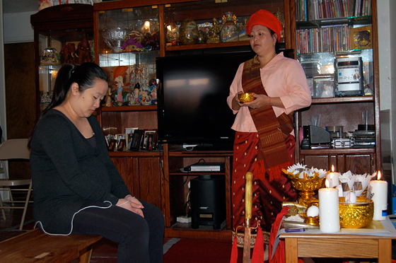 A Hmong shaman blesses a young pregnant woman in rural Merced