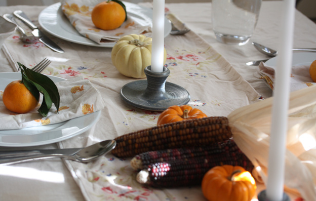 Dining table set for the holidays with linens, candlesticks, clementines and gourds. Photo: Nicole Spiridakis for NPR