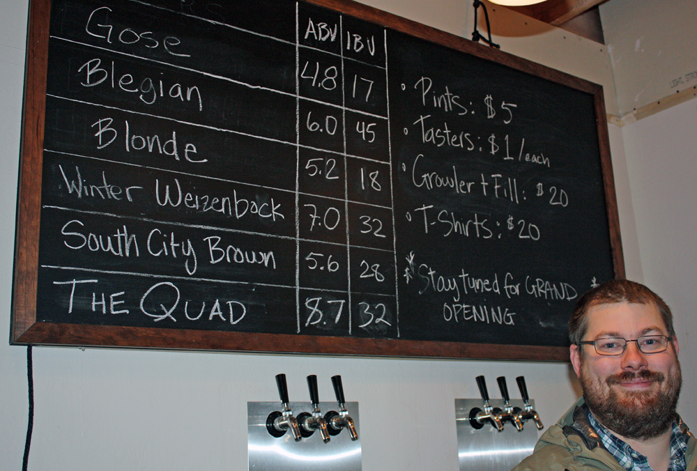 Nick Armstrong with the blackboard of beers available on tap in the tasting room at Armstrong Brewing Co. in South San Francisco.