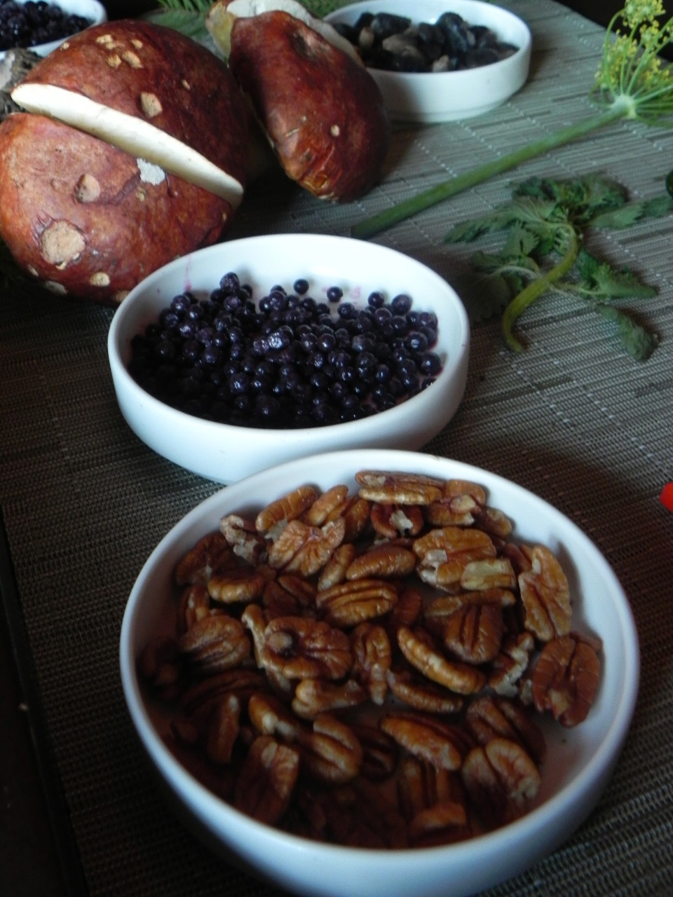 A display of the various edibles Stewart found in the Sierra Nevada. From bottom to top: a bowl of wild pecans, elderberries, Sierra porcinis and huitlacoche which he describes as corn infected with fungus.