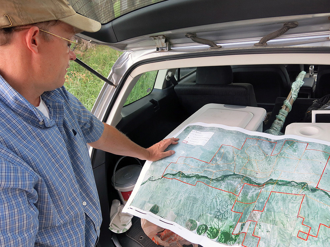 Ecologist William Burnidge checks a map of Fox Ranch that details the different areas rancher Nathan Andrews can graze his cattle. Photo: Luke Runyon/Harvest Public Media