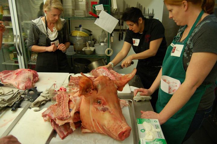 Bailie (center) working on a whole pig with class guests Photo: Ryan Harris