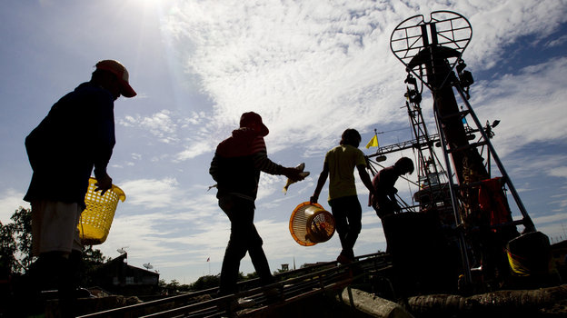 Migrant workers from Myanmar return to a trawler after unloading fish following a fishing trip in the Gulf of Thailand in Samut Sakhon province Tuesday. A new report details "deceptive and coercive" labor practices in the Thai fishing sector, which relies heavily on workers from Cambodia and Myanmar, also known as Burma. Photo: Sakchai Lalit/AP