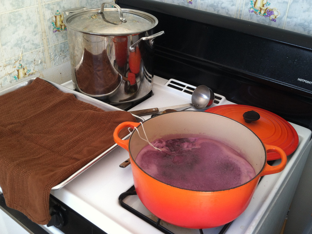 I don’t have a counter next to my stove, so I place a towel-lined baking sheet next to my boiling jelly as a landing pad for the mason jars (sterilizing in the stockpot in the back). The jelly should be cooking at a rolling boil, pictured bottom right. Photo: Kate Williams