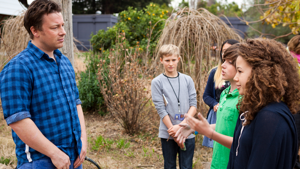Jamie Oliver listens to students talk about the program in the garden. Photo: Erin Scott