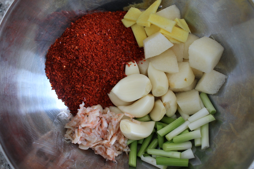My chili paste includes, from top left and moving clockwise, Korean kochukaru chili flakes, sliced ginger, chopped Asian pear, scallion whites, salted shrimp, and whole garlic cloves. Photo: Kate Williams