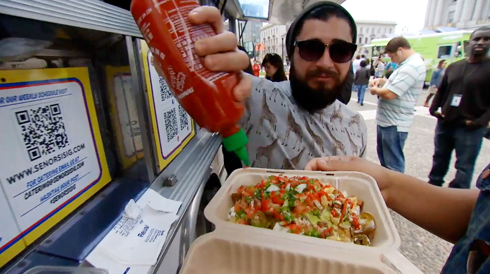 Señor Sisig food truck customer embellishes meal with Sriracha sauce