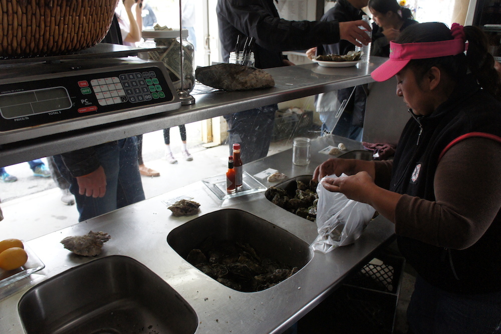Lorena Pablo serves customers some oysters from inside the shack. Photo: Angela Johnston