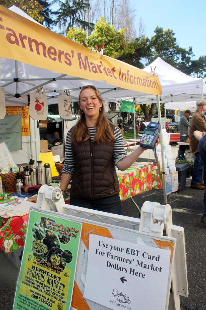 CalFresh benefits are exchanged at this booth for tokens to allow customers to shop at a farmers' market. Here, former Berkeley farmers' market Manager Katie Hannon Michel staffs the booth. Photo: Courtesy of the Ecology Center.