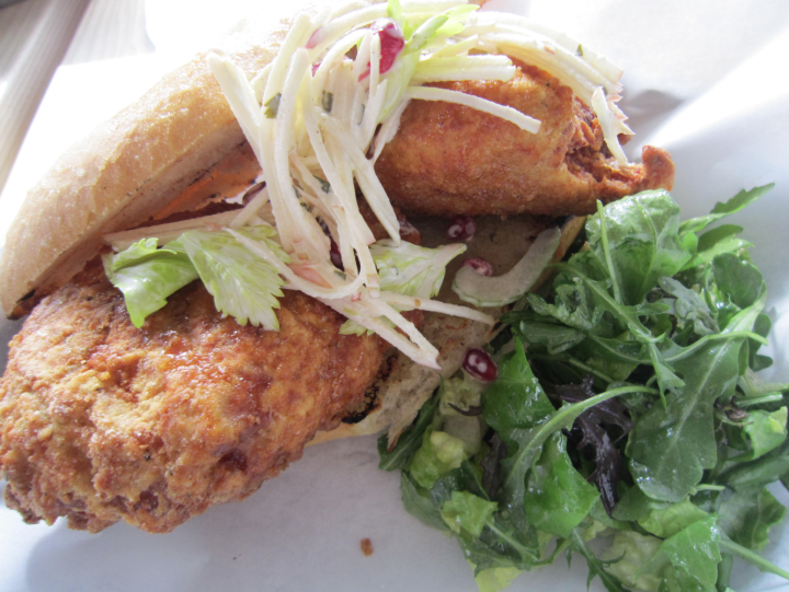 The Fried Chicken: with fish sauce caramel, Old Bay Butter, apple celery leaf slaw, and pomegranate seeds on a French hero roll. Photo: Alix Wall