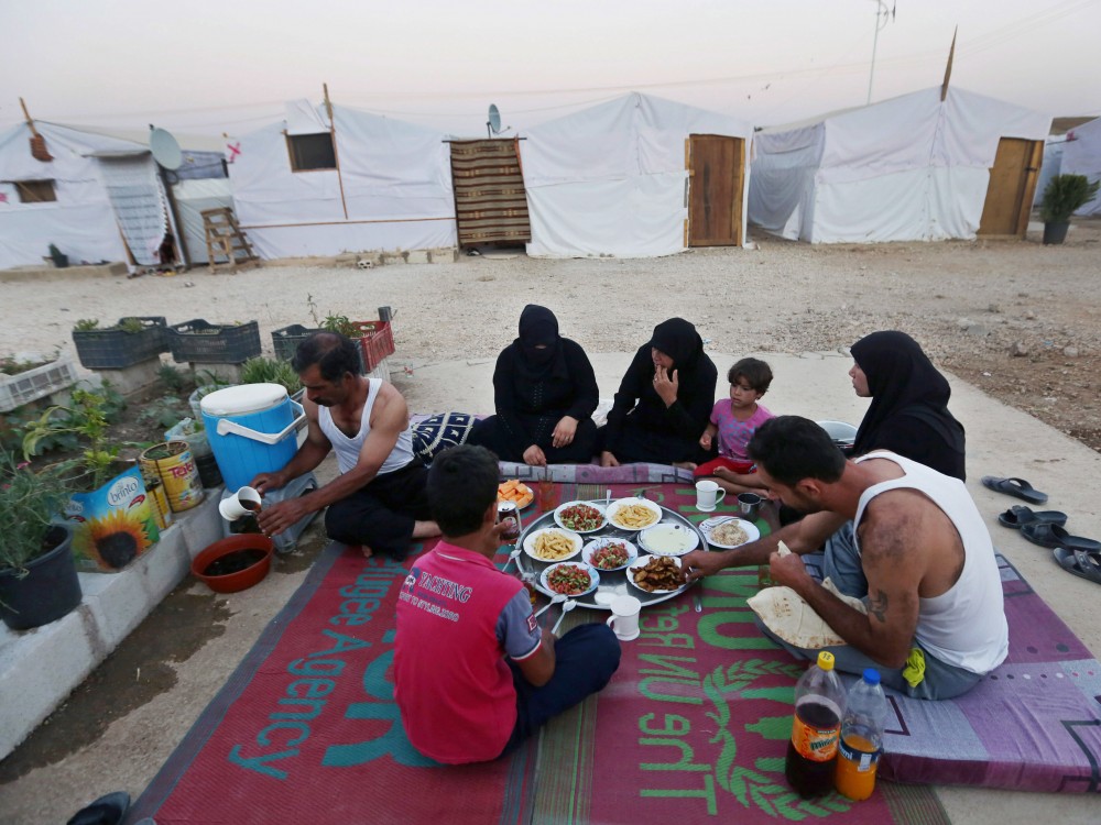 Syrian refugees break their fast outside their tent at a Syrian refugee camp in Marj, Lebanon, on June 29. The World Food Program says it has suspended a food voucher program serving more than 1.7 million Syrian refugees because of a funding crisis. Photo: Bilal Hussein/AP