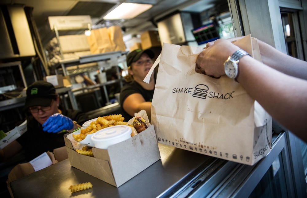Customers pick up their orders from a Shake Shack in New York City. It's one of the restaurants whose labor practices are detailed in the ROC United Diners' Guide app. Photo: Andrew Burton/Getty Images