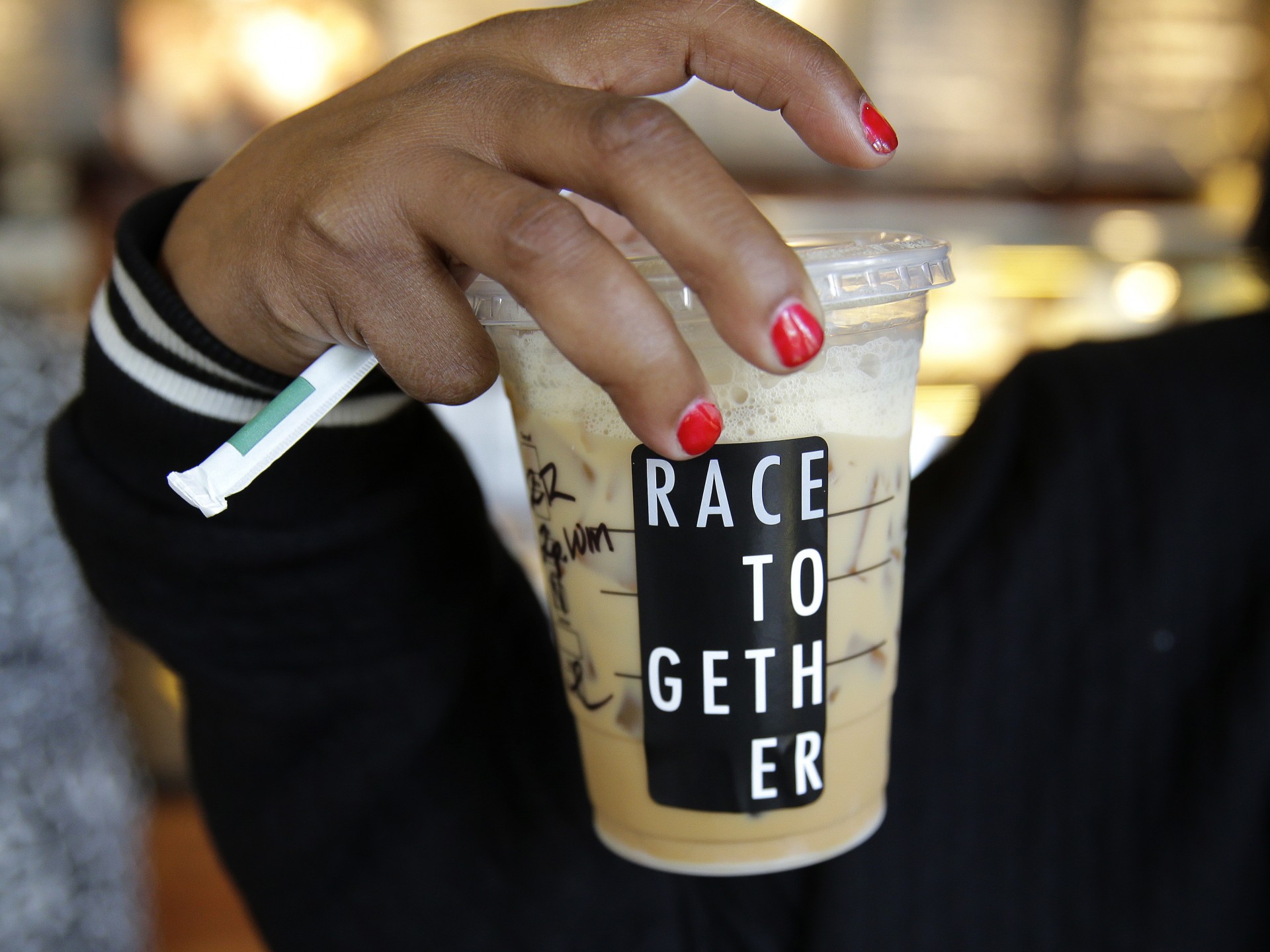 Larenda Myres holds an iced coffee drink with a "Race Together" sticker on it at a Starbucks store in Seattle. Starbucks baristas will no longer write "Race Together" on customers' cups starting Sunday. Photo: Ted S. Warren/AP