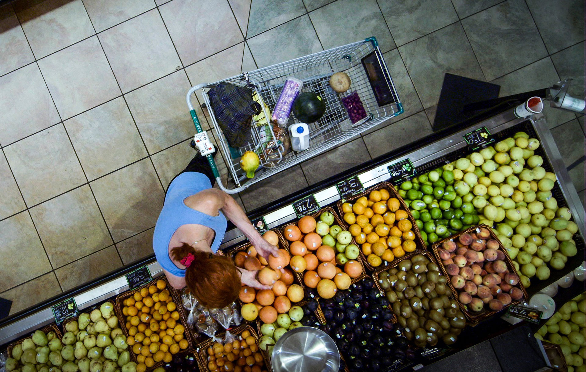 A grocery shopper picks through fruit in the produce section. Most fruits and vegetables are culled due to aesthetic issues rather than safety concerns.