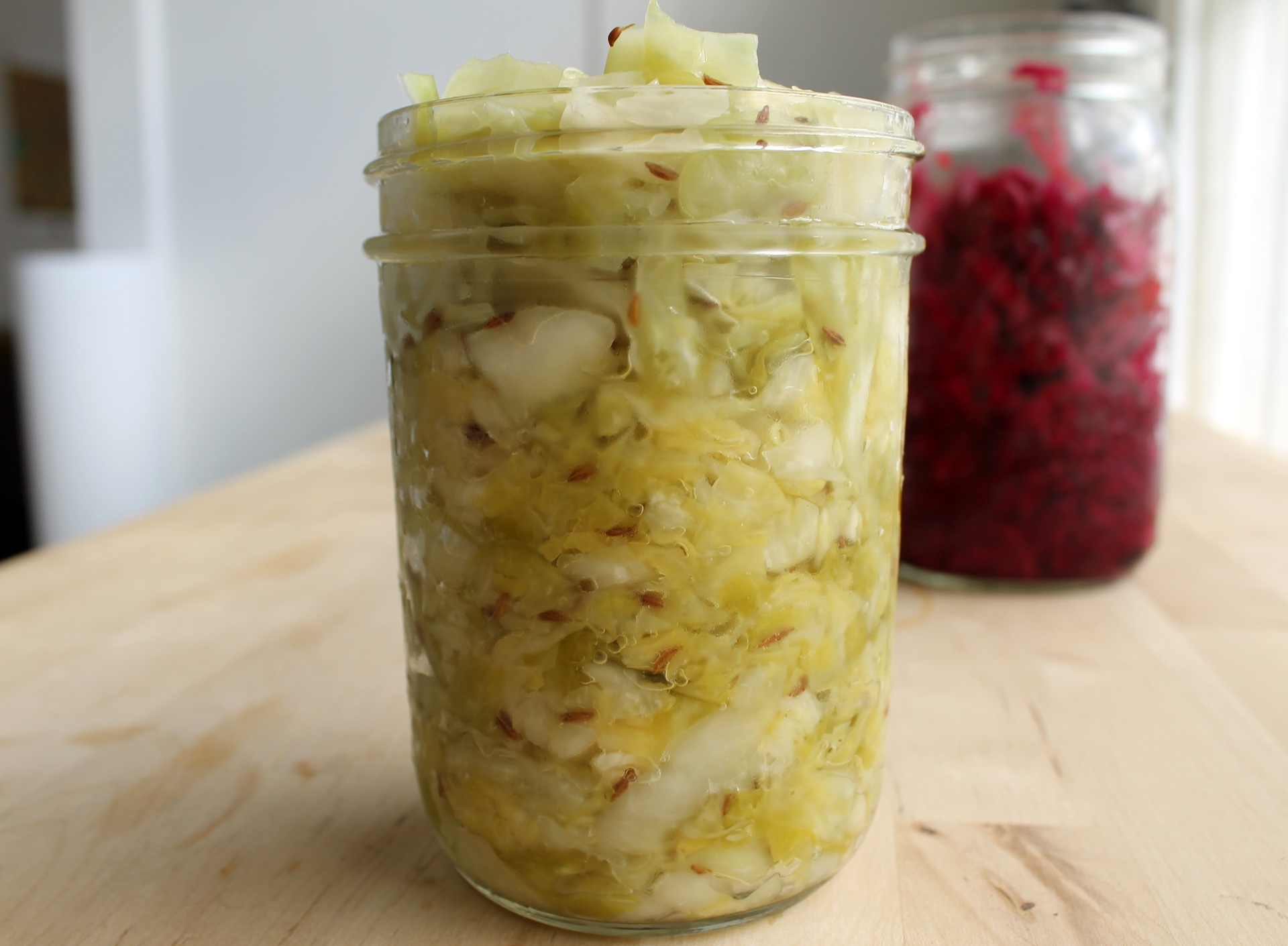 The fully fermented kraut will have visible bubbles inside the jar and will have dulled in color.