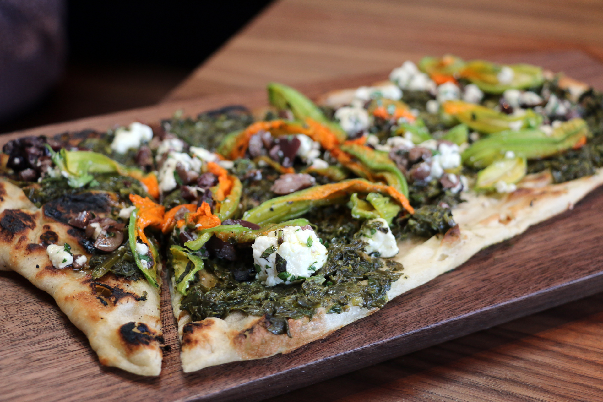 Flatbread with spinach, feta, squash blossoms, and olives from the wood-burning oven.