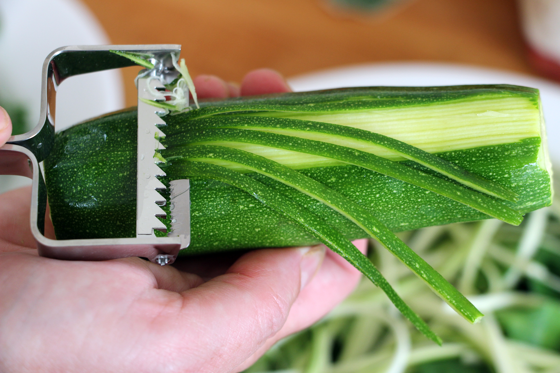 Creating zucchini “noodles” with a julienne peeler.