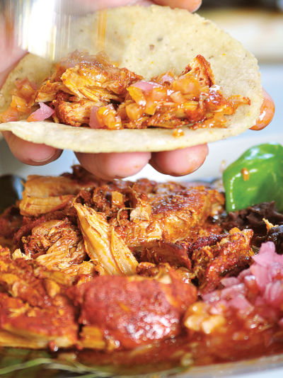 The name of these tacos, "cochinita pibil," tells you what's inside: young pig cooked in an oven pit. It's a traditional Mayan dish that originated after the Spanish conquistadors arrived, bringing pigs with them.
