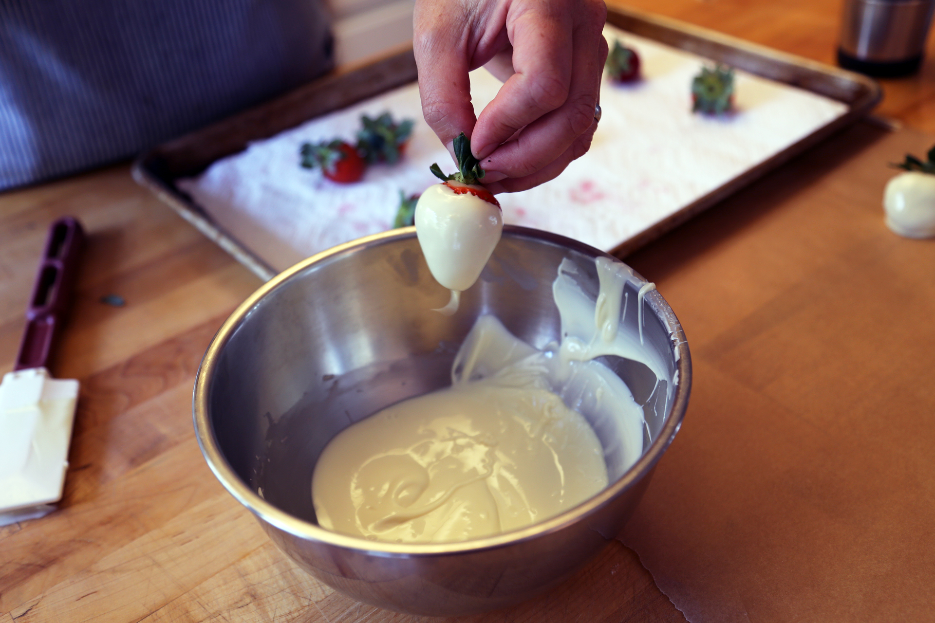 Holding the leaves on the stem, dip each strawberry into the melted white chocolate to coat, letting the excess drip off.