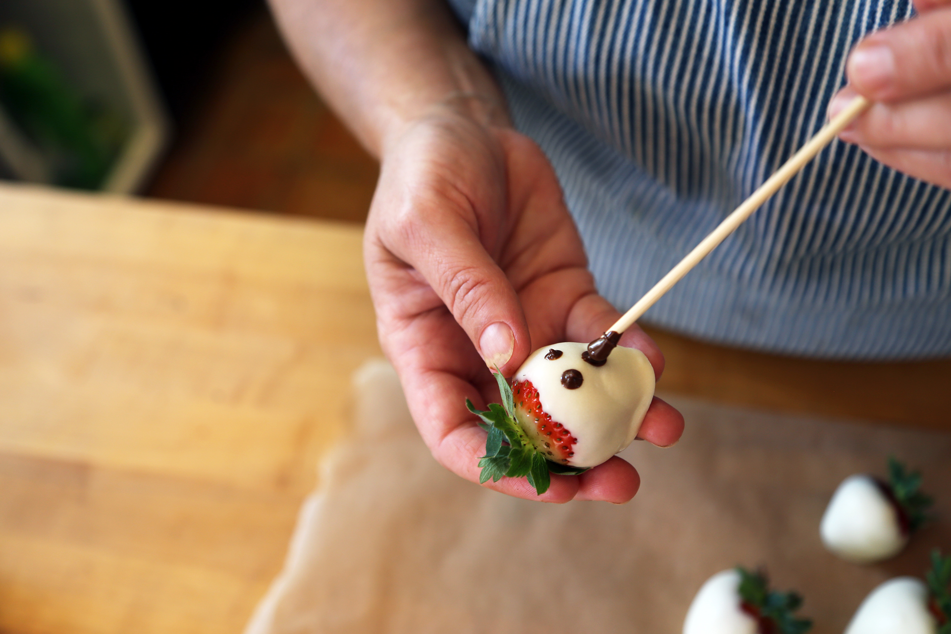 Using a toothpick or wooden skewer, draw eyes and a ghoulish mouth on each strawberry.