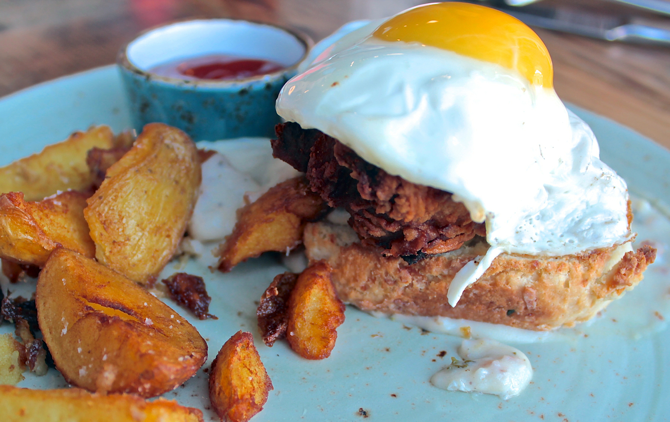 Fried chicken at The Table served over a cheddar cheese biscuit with country sausage gravy and a fried egg.
