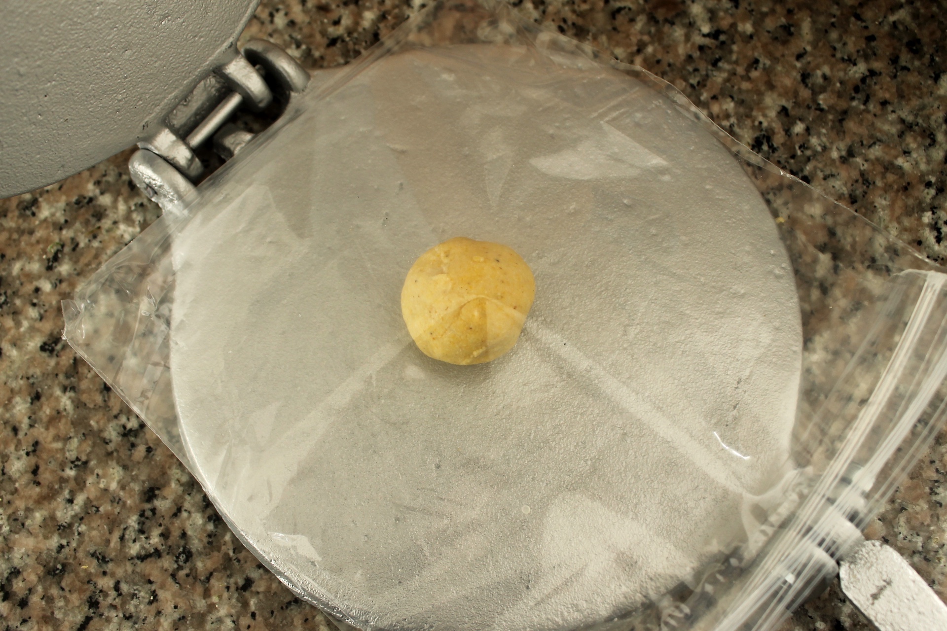 Place the ball of dough between the two layers of plastic in the center of the tortilla press.