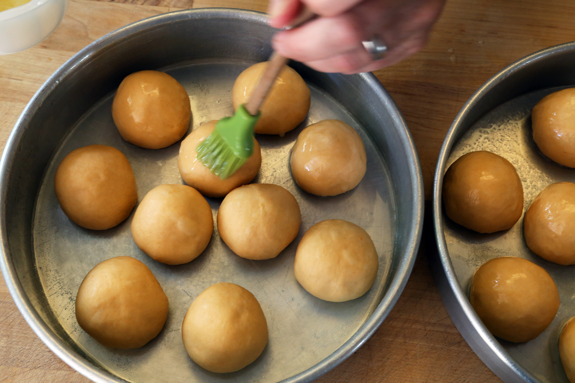 Place half of the balls into each prepared cake pan, spacing them evenly. Brush the dough balls with half of the melted butter. 