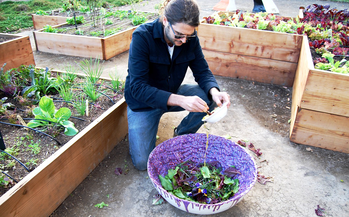 Los Angeles artist Michael Parker pours a dressing of lemon juice, olive oil, salt and pepper over edible flowers, herbs and greens. Parker also made this giant purple porcelain bowl.