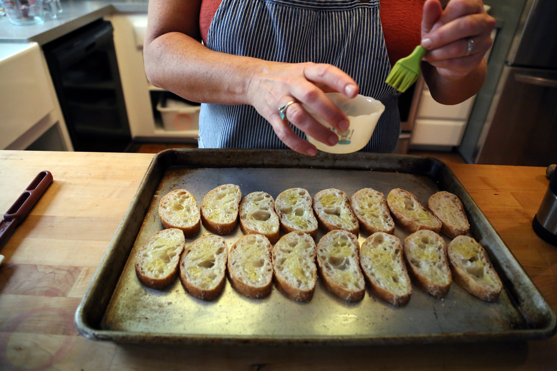 Brush both sides of each baguette slice with olive oil and place on a baking sheet. Toast in the oven until golden brown, about 10 minutes.