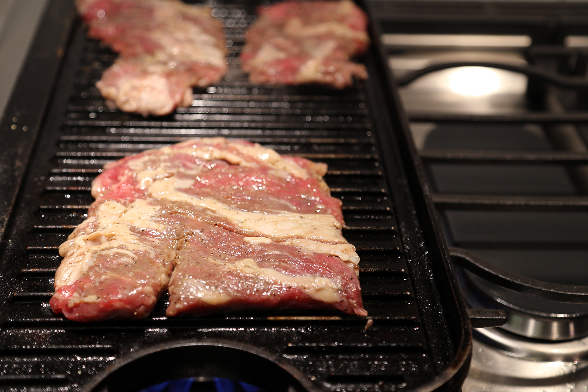 To make the steak, season it liberally with salt and pepper and drizzle it with olive oil. Prepare a gas or charcoal grill for medium-high direct heat or heat a stovetop grill on the stovetop.