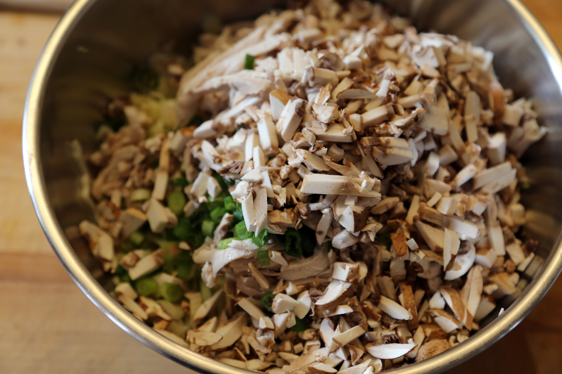 In a large mixing bowl, toss together the shredded chicken, cabbage, mushrooms, green onions, and water chestnuts.