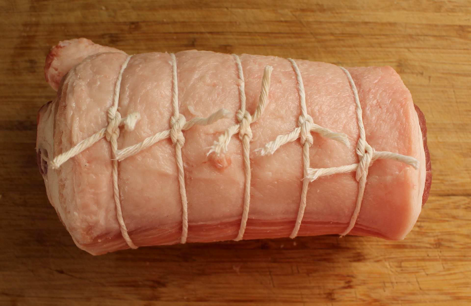  Roll the pork belly into a tight cylinder and then tie it at 1-inch intervals.