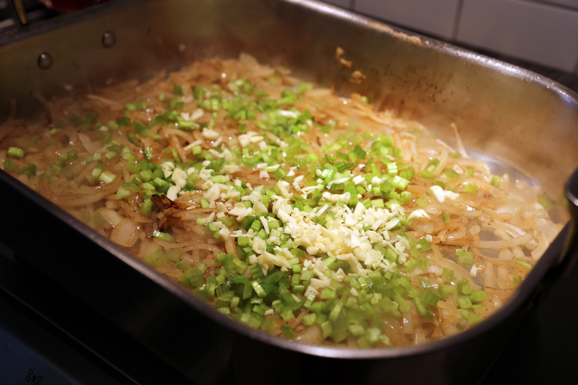 Add the sliced onions to the pan and stir with a wooden spoon to scrape up any browned bits stuck to the bottom. Cook until golden and softened, about 10 minutes. Stir in the celery.