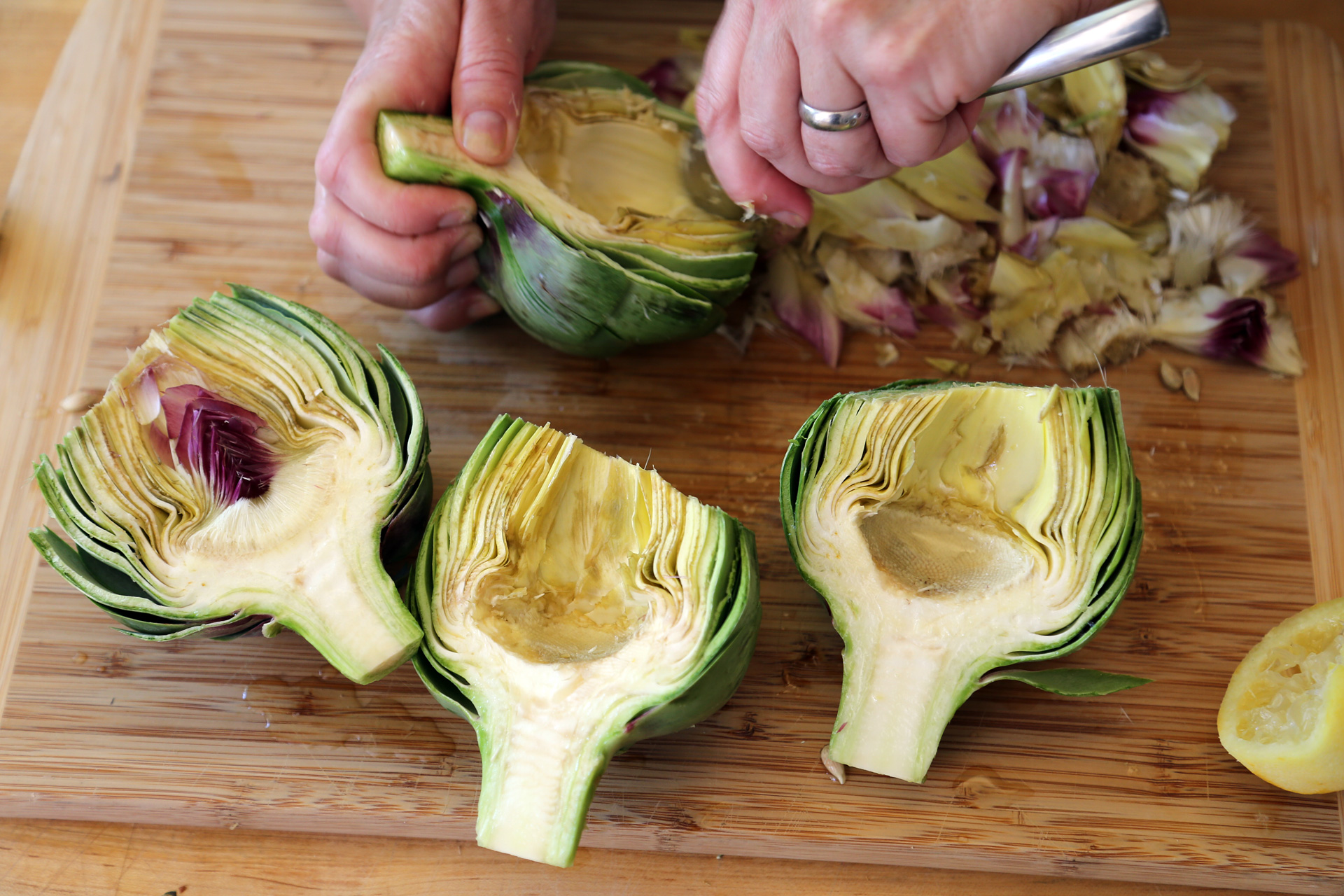 Use a small metal spoon to scoop out and remove the fuzzy chokes and the smaller inner leaves; discard. Rub the artichoke halves all over with the lemon.