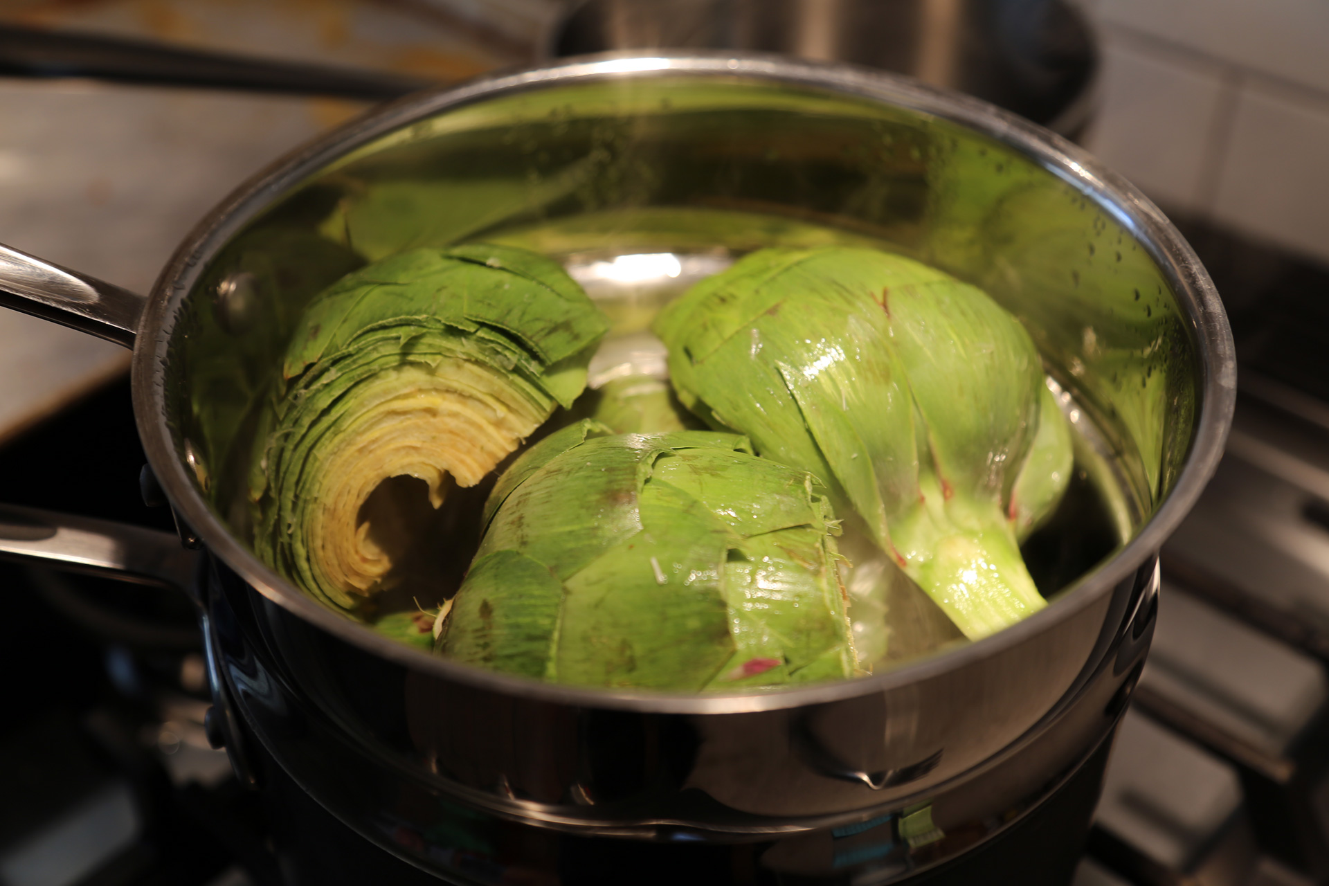 Fill a large pot with about 1 inch of water and fit with a steamer basket. Bring the water to a boil over high heat and add the artichoke halves, cut sides down.
