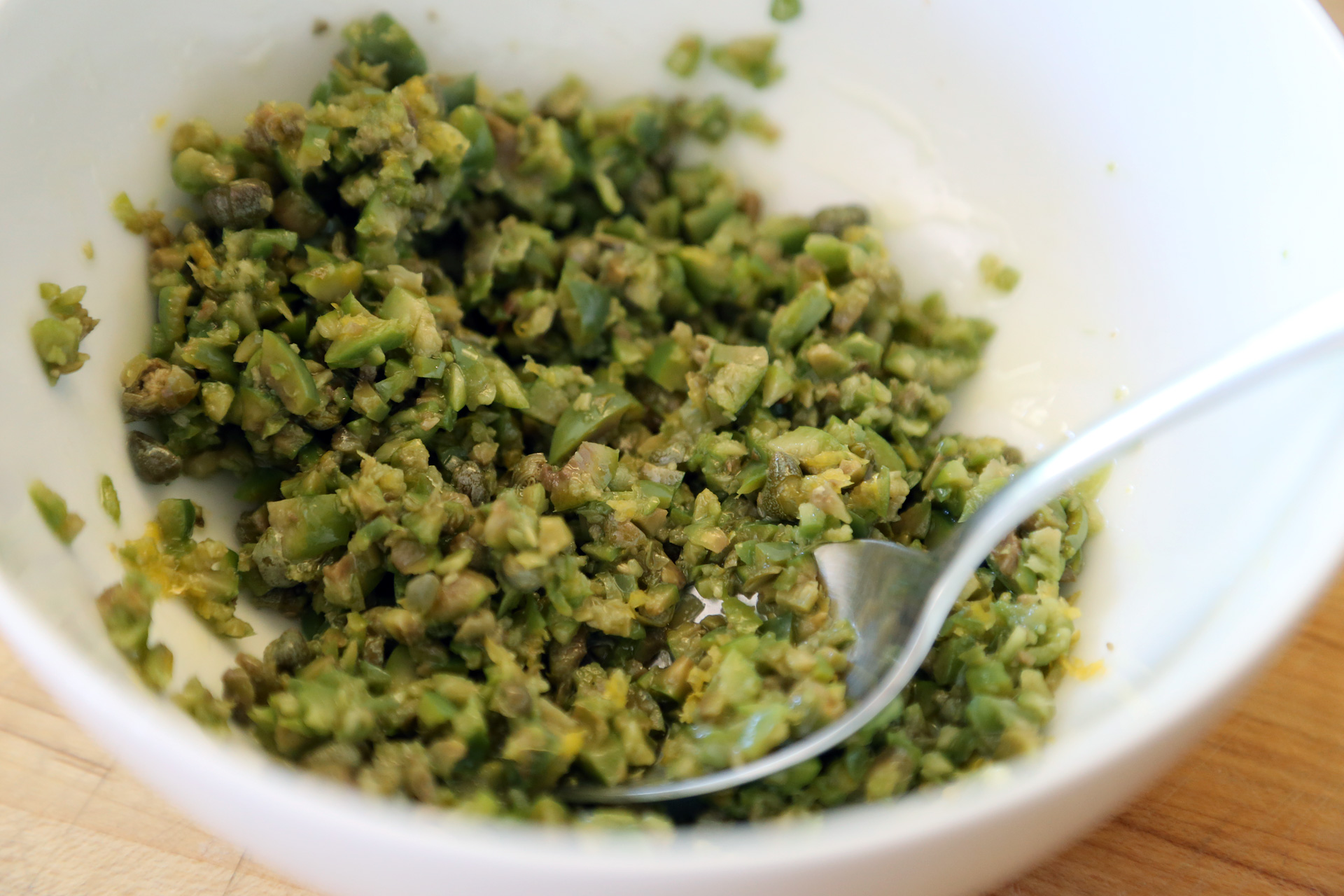 To make the relish, in a bowl, stir together the minced olives, lemon zest, capers, and olive oil. Set aside.