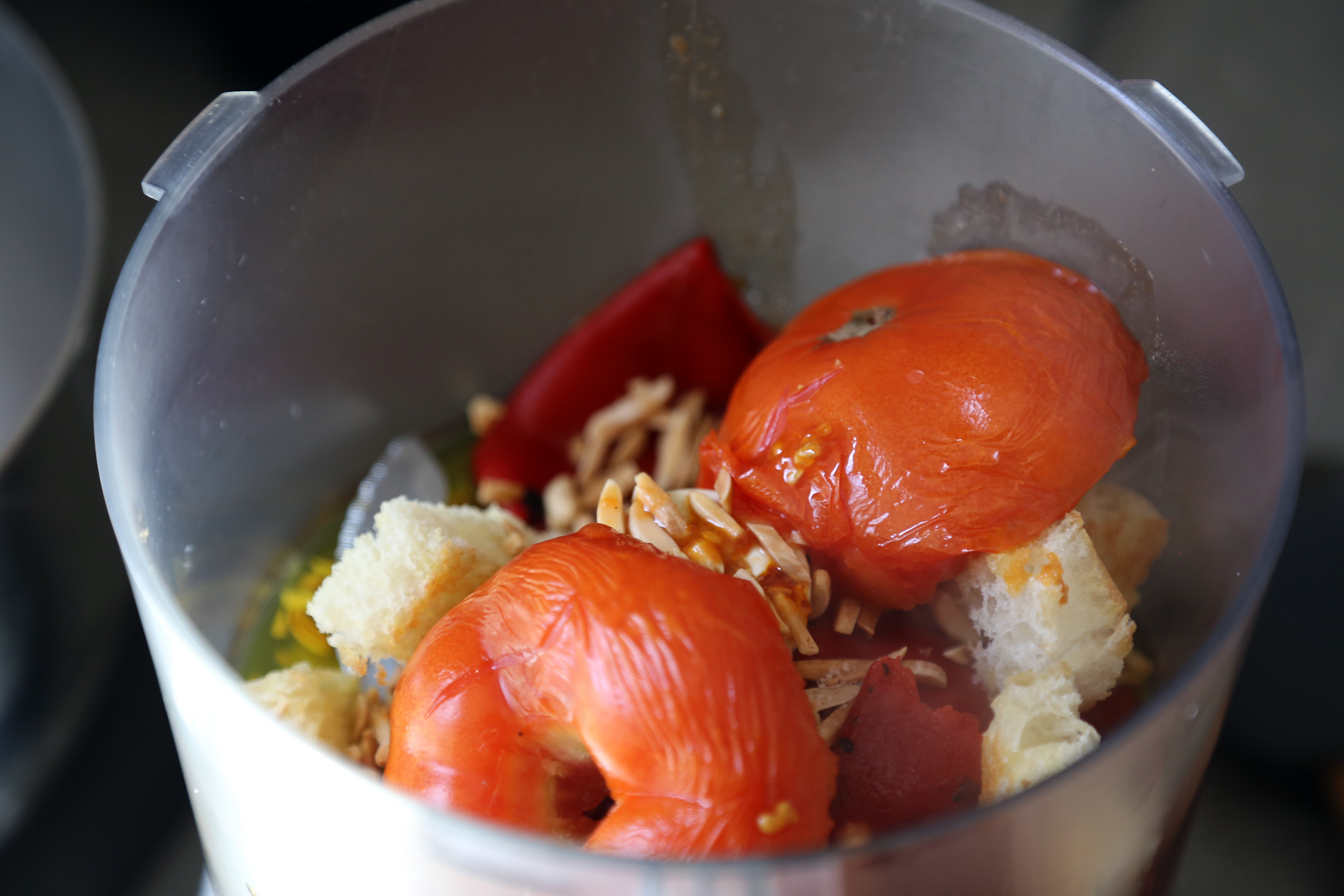 Continue to roast the tomato and garlic for another 10 minutes. Remove the tomato peel and discard. Transfer the tomato and garlic to the food processor.