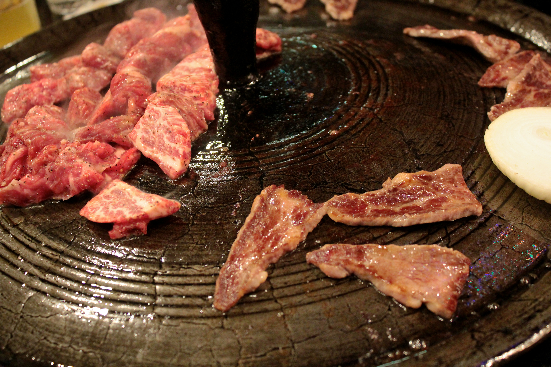 Boneless pieces of short rib marinated in salt and pepper cooking on the griddle at Gooyi Gooyi.