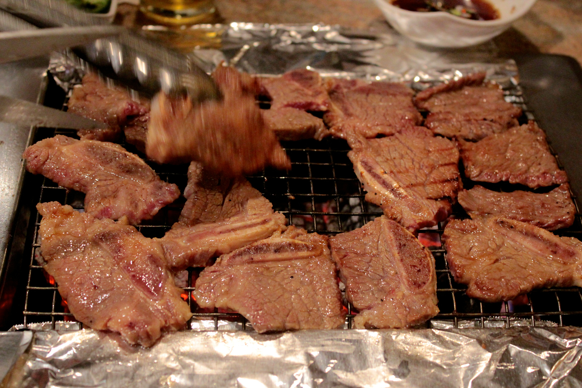 A server cooks short ribs on the charcoal grill at Han Sung.